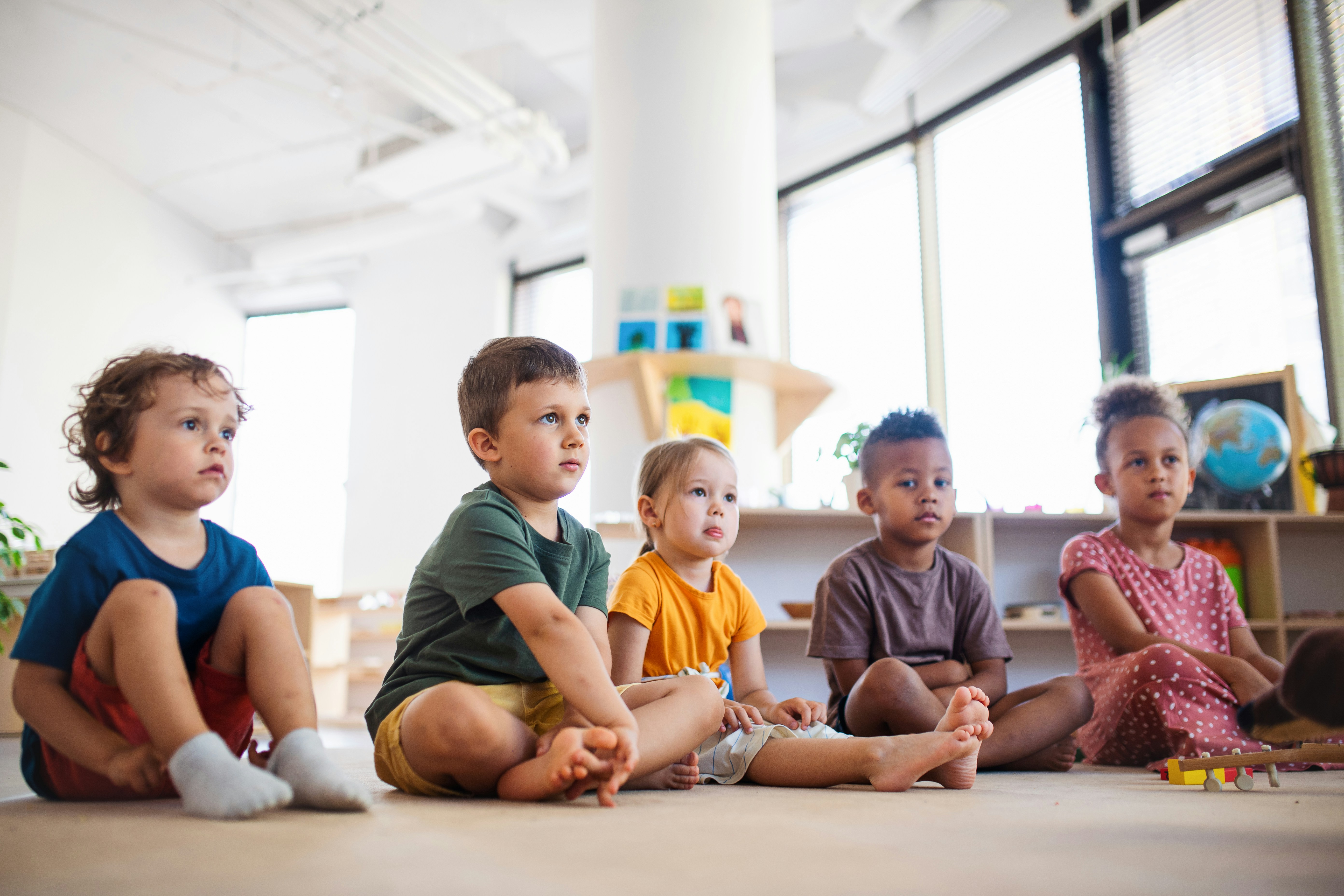 Preschool children gathered around a teacher asking questions